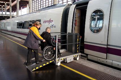 Usuario en silla de ruedas atendido por asistente servicio Atendo en el acceso al tren